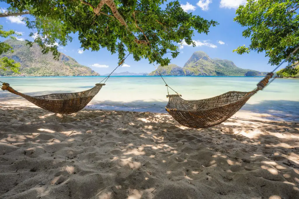 El Nido, Palawan, Philippines. Bamboo hammocks on shore in the shade. Beautiful tropical lagoon with