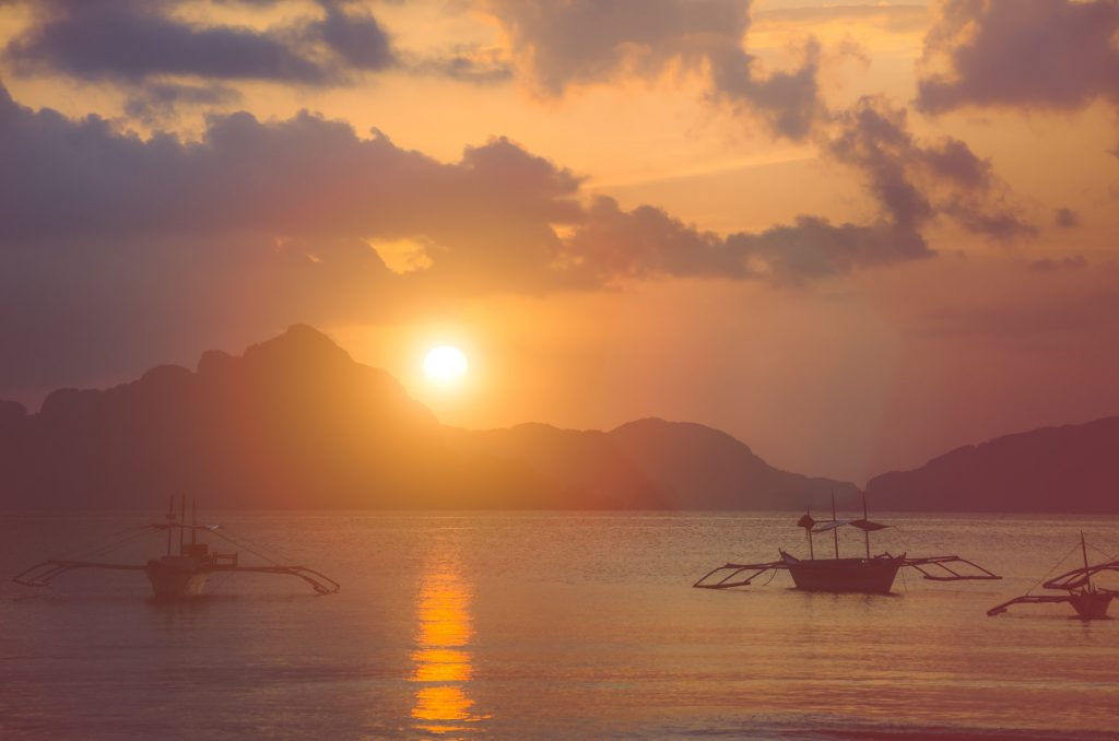 Sunset at El Nido. Banca boat anchored in a bay. Palawan island, Philippines